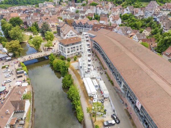 Aerial view of a town by the river with a Ferris wheel and red tiled roofs under a clear sky, 950 years of Calw, Calw parade, Black Forest, Germany