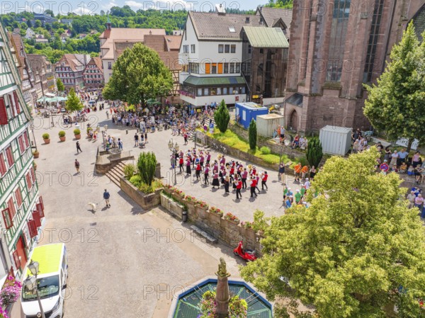People in traditional dress make music on a busy town square next to historic buildings, 950 years of Calw, Calw parade, Black Forest, Germany