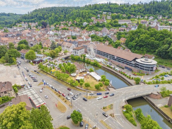 Wide view of a town with river and Ferris wheel in the middle of a green and mountainous environment, 950 years of Calw, Calw parade, Black Forest, Germany