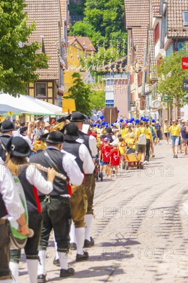 People in traditional dress parade cheerfully through a sunny village street, 950 years of Calw, Calw parade, Black Forest, Germany