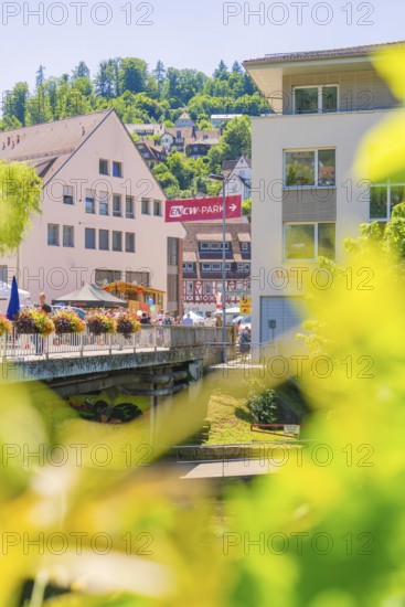 View of a town on a river with a bridge and lush summer greenery around the buildings, 950 years of Calw, Calw parade, Black Forest, Germany