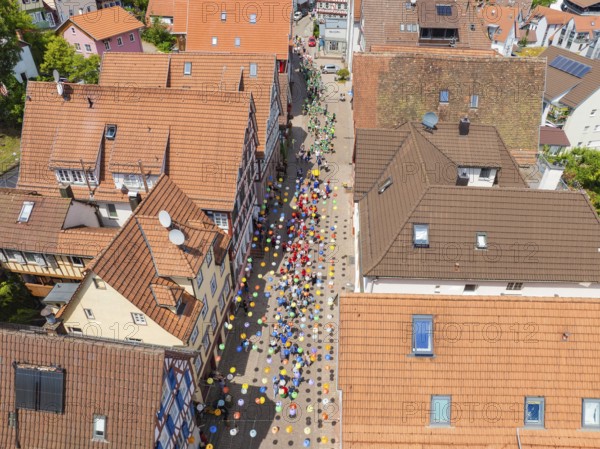 People walking on a street decorated with colourful umbrellas, 950 years Calw, parade Calw, Black Forest, Germany