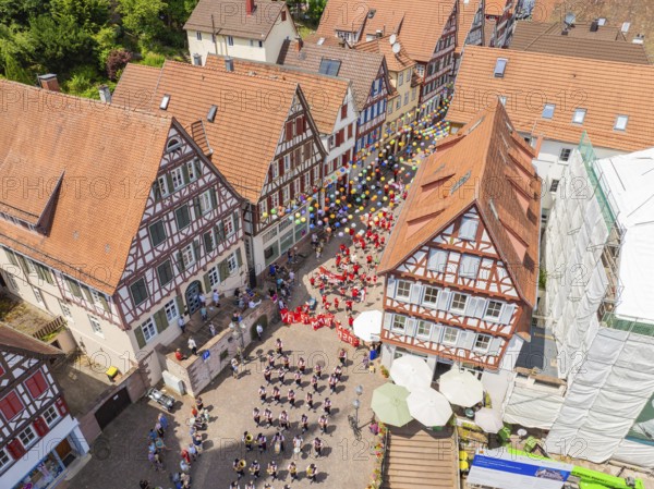 From above you can see people in formation and colourful balloons next to historic house facades, 950 years of Calw, Calw parade, Black Forest, Germany