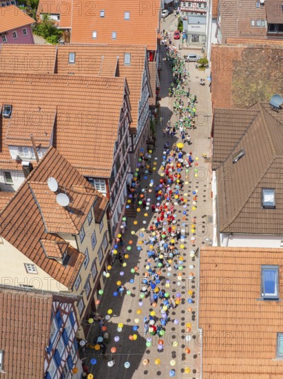 Colourful balloons decorate a busy street, surrounded by houses with red tiled roofs, 950 years of Calw, Calw parade, Black Forest, Germany