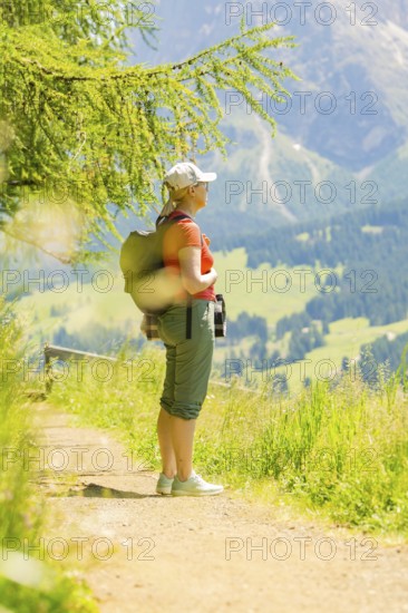 Person hiking on a sunny path in a mountainous and green landscape, Alpe di Siusi, Dolomites, South Tyrol, Italy
