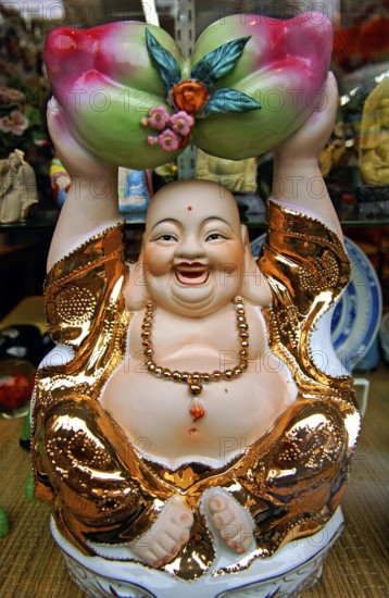 Buddah figure in a shop window, China Town, New York City, USA