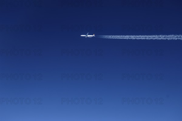 View of a passing aircraft in the blue sky at an altitude of 10, 000 metres, Atlantic flight to New York, USA
