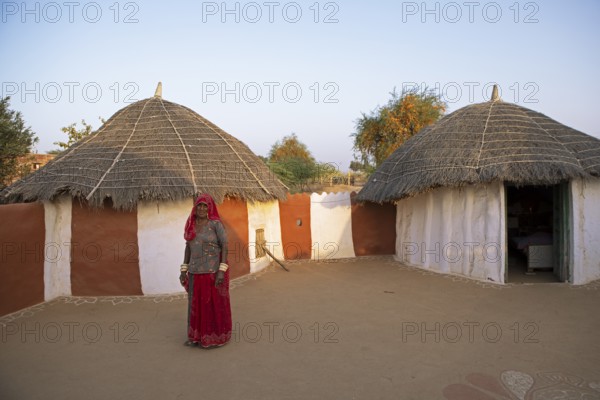Indian woman, 55 years old, desert dweller, behind typical round buildings in the Thar Desert or Great Indian Desert, near Jaisalmer, Rajasthan, India