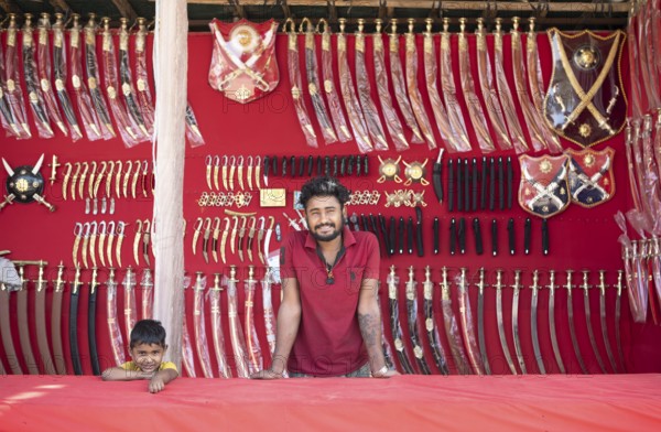 Indian man and boy at a market stall for weapons in the Thar Desert or Great Indian Desert, near Jaisalmer, Rajasthan, India