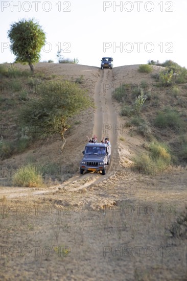 Jeeps driving down a sand dune in the Thar Desert or Great Indian Desert, near Jaisalmer, Rajasthan, India