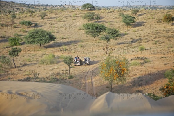 Jeeps waiting under a dune in the Thar Desert or Great Indian Desert, near Jaisalmer, Rajasthan, India