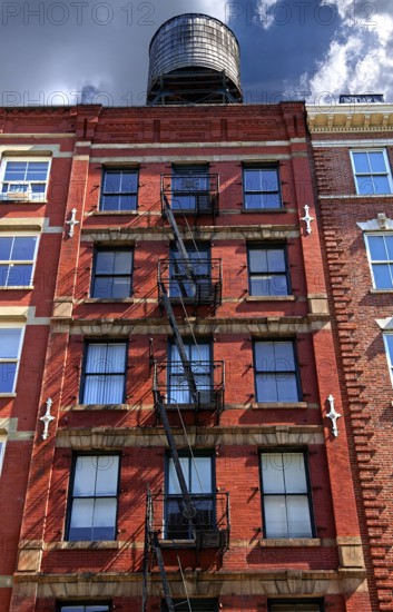 Residential building with fire escapes and wooden water tank on the roof, Downtown NY, New York City, USA