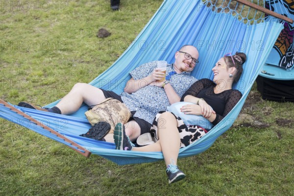 Two festival visitors lying in a hammock in the Fashion Palooza at the Lollapalooza Festival in the Olympiastadion and on the Maifeld, Berlin, 13 July 2025