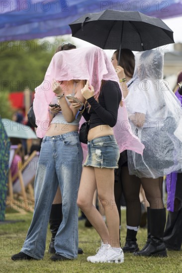 Festival-goers stand in a queue protected by rain capes at the Fashion Palooza at the Lollapalooza Festival in the Olympic Stadium and on the Maifeld, Berlin, 13.07.2025
