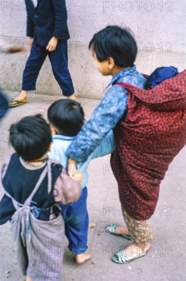 NB Poor focus. Child carrying baby looking after young children, Tai Po, New Territories, Hong Kong, Asia, 1964