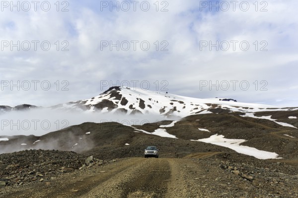 Range Rover drives through volcanic landscape with snow remains, off-road vehicle on gravel track to Jöklasel, Höfn, Austurland, Iceland