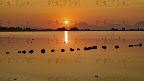 Dramatic sunset over a calm lake with mountain silhouette, salt lake, Tigaki, nature reserve, hydro biotope, Kos, Dodecanese, Greek Islands, Greece