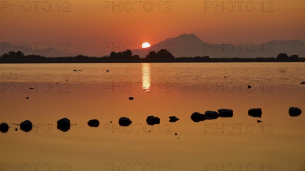 Warm sunset light reflected in the calm lake with mountain backdrop, salt lake, Tigaki, nature reserve, hydro biotope, Kos, Dodecanese, Greek Islands, Greece