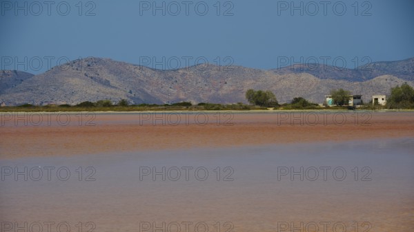 Mountainous landscape with calm lake and small huts under a bright blue sky, salt lake, Tigaki, nature reserve, hydro biotope, Kos, Dodecanese, Greek Islands, Greece