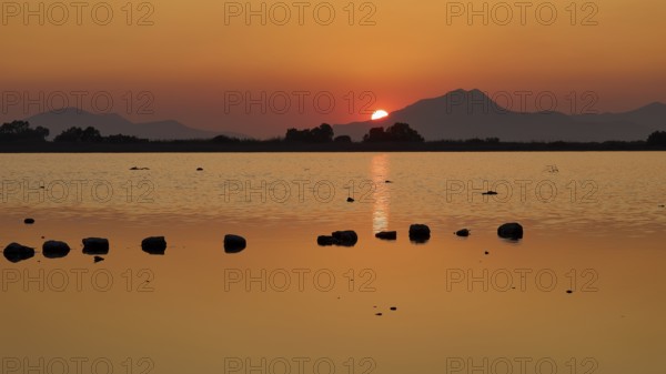 Idyllic scene with setting sun behind a lake and mountains, salt lake, Tigaki, nature reserve, hydro biotope, Kos, Dodecanese, Greek Islands, Greece
