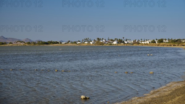 A coastal village on the shore of a lake in calm weather under a blue sky, salt lake, Tigaki, nature reserve, hydro-biotop, Kos, Dodecanese, Greek Islands, Greece