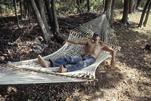 Young man with sunglasses and cap sleeping in a hammock, New Jersey, USA