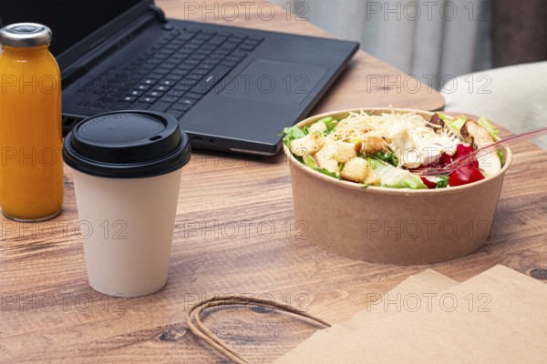 Work at home on a laptop, there is food on the table, salad, coffee and juice, delivery, there are no people
