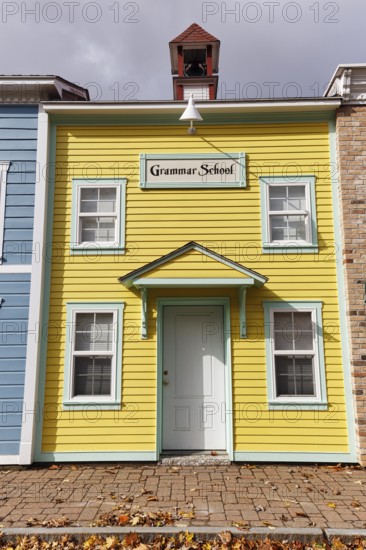 Replica, historic elementary school, yellow façade, sign, fall leaves, boutique hotel, theme hotel Adventure Suites Hotel, North Conway, Kancamagus Highway, White Mountain, New Hampshire, New England, USA