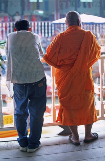 A monk and another man watch the hustle and bustle at Damnoen Saduak Floating Market, Thailand, December 2002, vintage, retro, old, historic