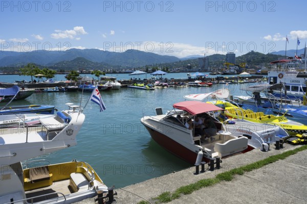 A busy port with adjacent yachts and boats, mountains and blue sky in the background, Batumi, Black Sea, Ajara region, Adjara, autonomous republic, Georgia
