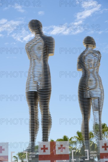 Metal figures of a woman and a man against a blue sky, Georgian flags at the bottom of the picture, the statue of Ali and Nino, Batumi, Black Sea, Ajara region, Adjara, autonomous republic, Georgia