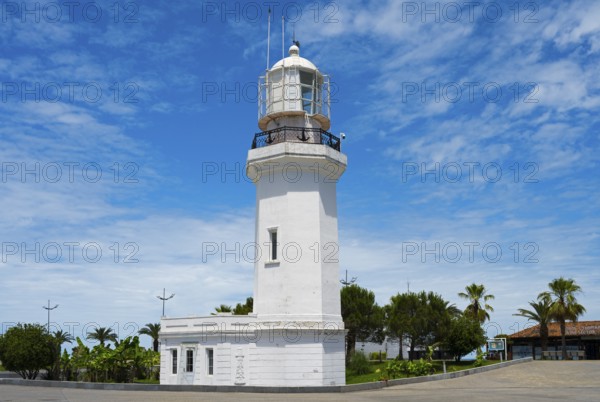 White lighthouse against a blue sky with some clouds surrounded by palm trees and vegetation, lighthouse, Batumi, Black Sea, Ajara region, Adjara, autonomous republic, Georgia