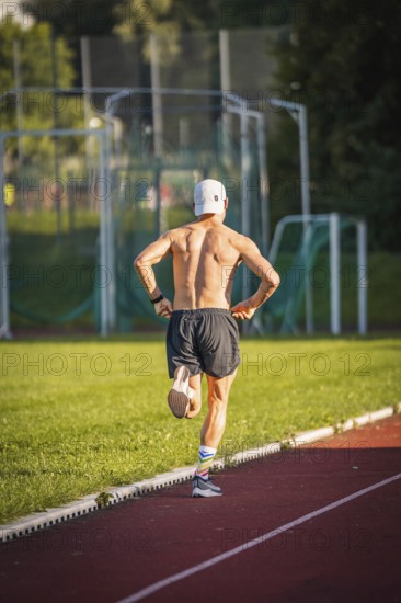 Runner jogging bare-chested on an outdoor running track, triathlon, Calw, Germany