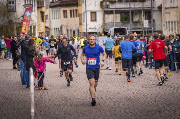 Runners and spectators on a paved road during a road race, triathlon, Calw, Germany