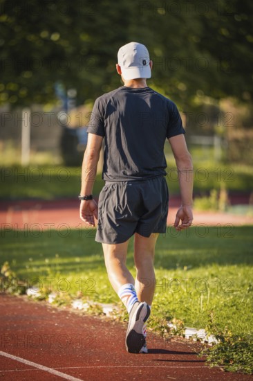 A person in sportswear runs on a running track in the middle of a green, summer environment, triathlon, Calw, Germany