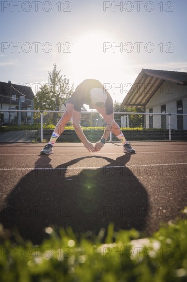 Person stretching on a running track at sunset, triathlon, Calw, Germany