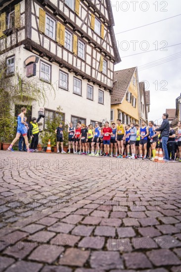 Group of runners on the starting line in front of timber-framed houses, spectators watching the race, Triathlon, Calw, Germany