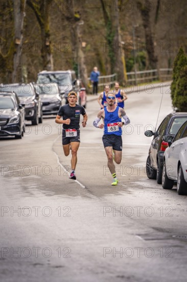 Two runners running on a road with parked cars and trees in the background, Triathlon, Calw, Germany