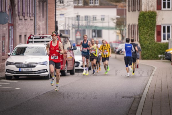 Runners in sportswear running on a rural road with parked cars, triathlon, Calw, Germany