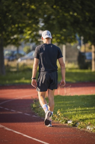 Athlete walks comfortably on a running track in diffuse sunlight, Triathlon, Calw, Germany