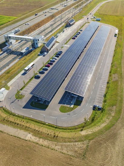 Large parking lot with solar panels along a road and fields, photographed from the air, e-charging park, Merklingen, Germany