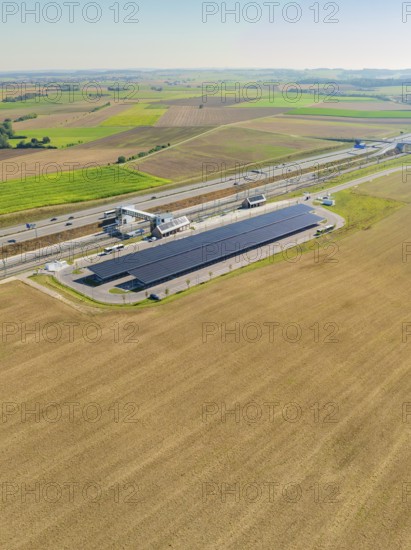 Solar system on a motorway in the midst of a flat landscape and fields, e-charging park, Merklingen, Germany