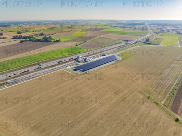 Extensive fields and solar system on a motorway under clear skies, e-charging park, Merklingen, Germany