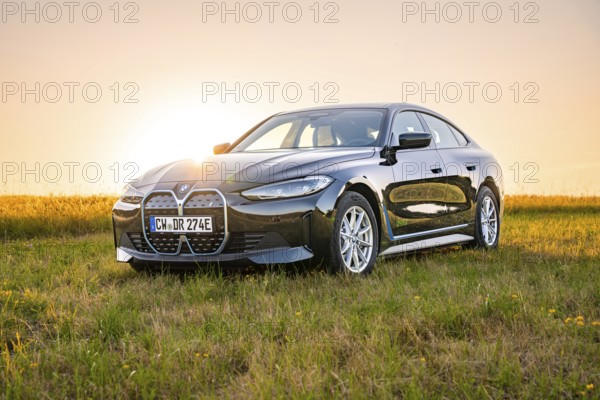 Black car in open field at sunset, natural environment, BMW i7 electric car, Deer E- Carsharing, Calw, Germany