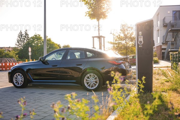 Black BMW at a charging station in an urban environment at sunset, BMW i7 electric car, Deer e-Carsharing, Calw, Germany