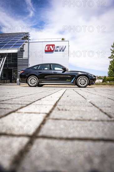 Black car on paving stones in front of a modern building under blue sky, BMW i7 electric car, Deer e-Carsharing, Calw, Germany