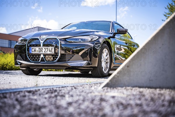 A black car presents itself under a blue sky in a parking lot, BMW i7 electric car, Deer e-Carsharing, Calw, Germany