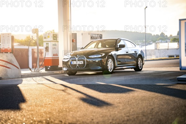 BMW at a gas station at sunset in an urban area, BMW i7 electric car, Deer e-Carsharing, Calw, Germany