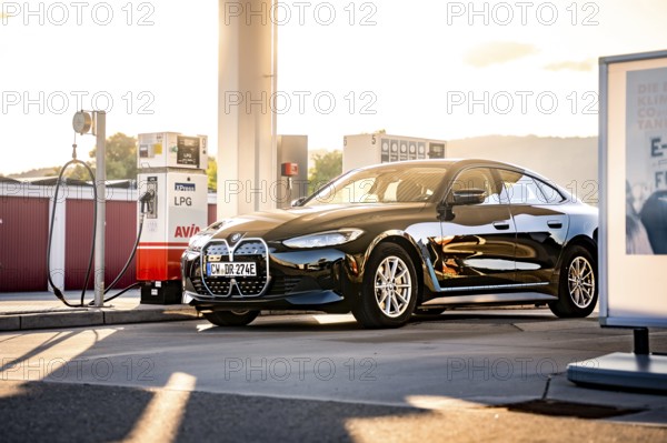 Black car at a gas station in the evening sun with modern architecture, BMW i7 electric car, Deer e-Carsharing, Calw, Germany