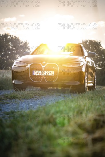 BMW with headlights switched on in the back light of sunset, BMW i7 electric car, Deer e-Carsharing, Calw, Germany